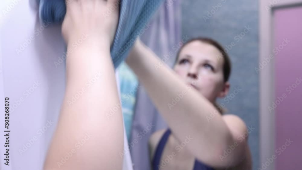 young woman wipes with a cloth the mirror in the bathroom young woman wipes with a cloth the mirror in the bathroom