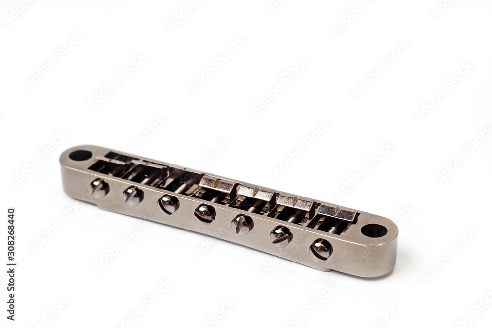 Metallic guitar bridge, suitable for electric and acoustic guitars, disassembled, closeup shot on a white background Metallic guitar bridge, suitable for electric and acoustic guitars, disassembled, closeup shot on a white background