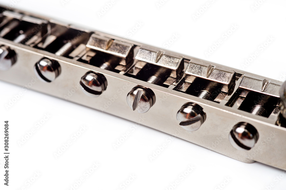Metallic guitar bridge, suitable for electric and acoustic guitars, disassembled, closeup shot on a white background