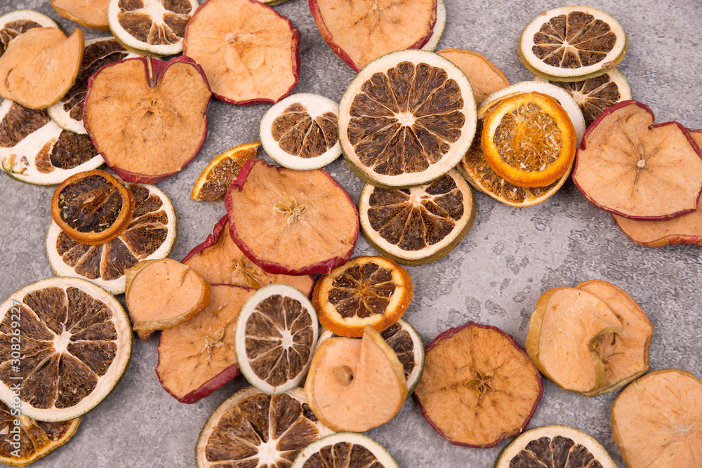 Dried lemon, orange and apple slices on a grey structured background
