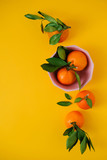 Tangerines in bowl on yellow background. Top view. Flat lay.
