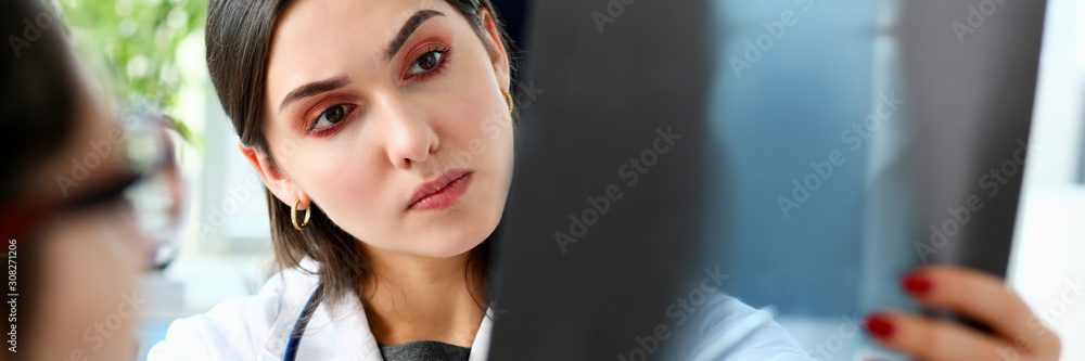 Female beautiful doctor hold in arm and look at xray Female beautiful doctor hold in arm and look at xray