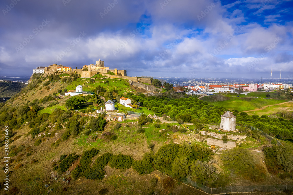 Aerial view of Palmela medieval Portuguese fortress castle and church near Setubal with wind mills, blue sky