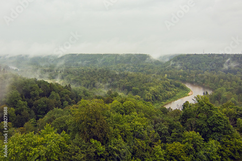 Aerial view on the river Gauja and National park Gauja with pine forest  from the main big tower of medieval Turaida Castle in cloudy  foggy and rainy day  Sigulda  Latvia. Soft focus