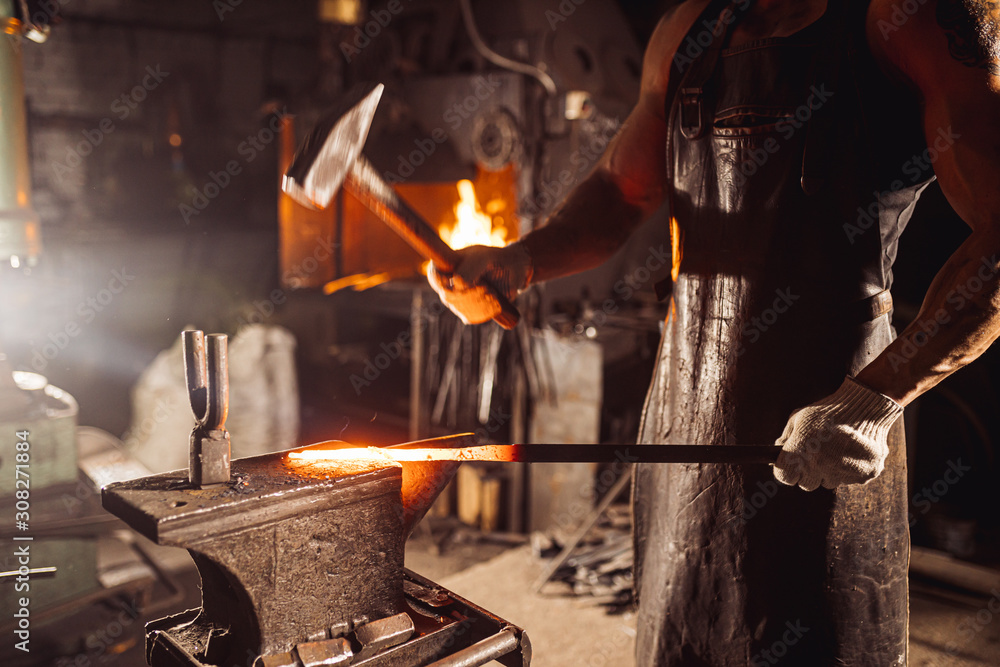 muscular adult with beard wearing leather apron working in workshop, heating. hardened metal in furnace muscular adult with beard wearing leather apron working in workshop, heating. hardened metal in furnace