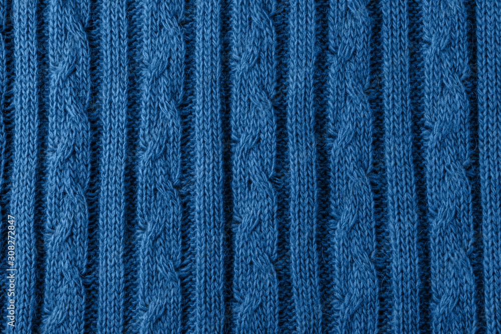 Fototapeta premium Fragment knit pattern of braid. Background of wool fabric tinted in fashionable color blue. Classic blue