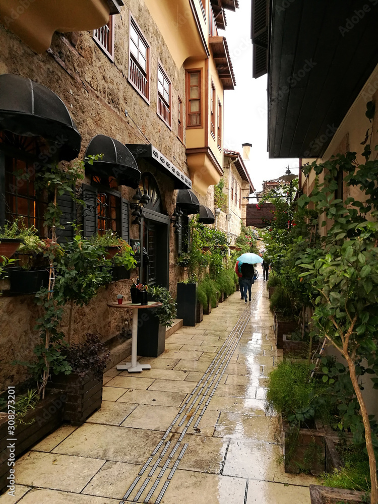 Fototapeta Narrow street in old town of Antalya. It is raining.