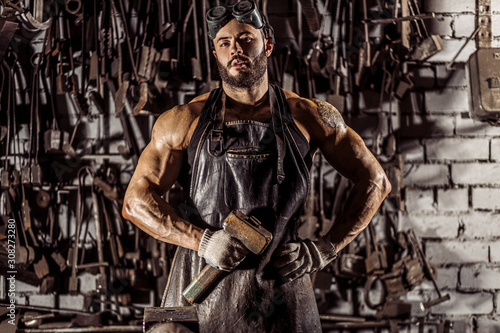 portrait of strong muscular blacksmith man wearing black apron, look confidently, have strong powerful hands and shoulders.