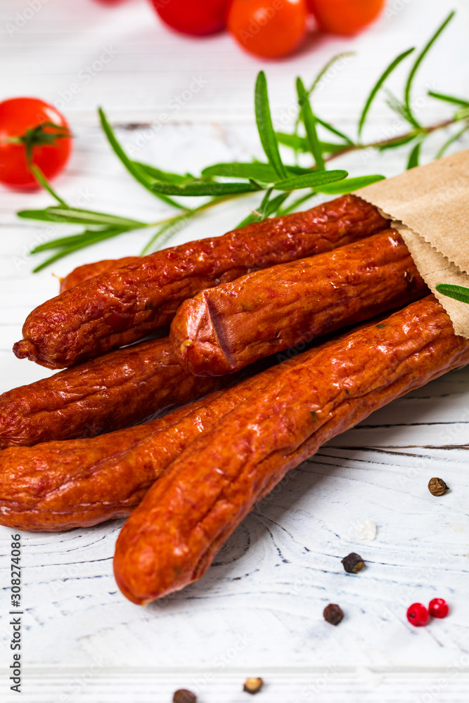 Thin Dry Smoked Polish Sausage Kabanos or Cabanossi on White Wooden Background. Selective focus. Thin Dry Smoked Polish Sausage Kabanos or Cabanossi on White Wooden Background. Selective focus.