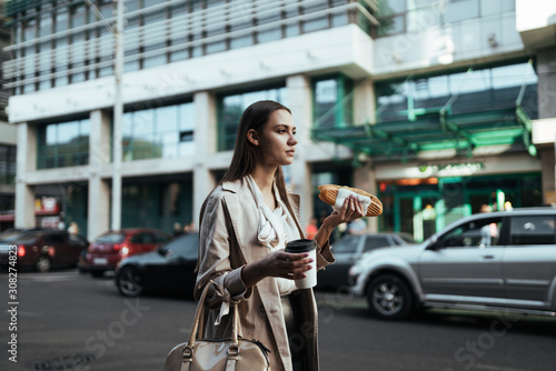 girl with a hamburger and coffee is walking down the street of the business center © mnelen.com