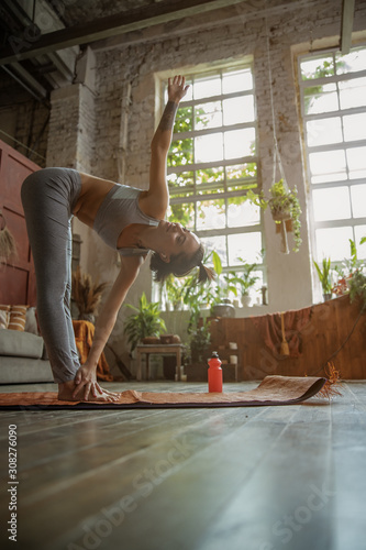 Fototapeta Naklejka Na Ścianę i Meble -  Pretty young lady doing yoga exercise at home