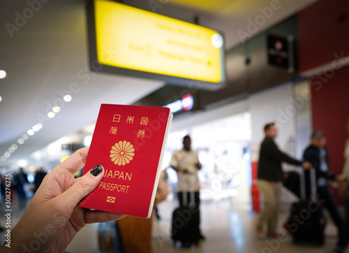 Close up of woman holding a Japan passport over a blurred airport background. Digital composite.Japan and Singapore have the world s most powerful passports, according to the Henley passport index