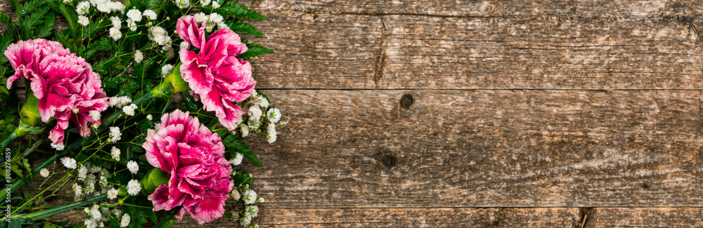 Fototapeta premium Top view of Carnation Flowers on White Vintage Wooden Background. Design concept for mothers day, wedding and valentines day with copy space. Selective focus.