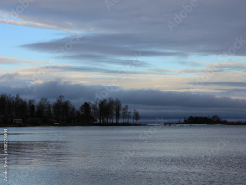 Trees at the shore of Lake Vanern and autumn clouds. © u.perreten