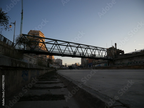 Dry riverbed of the Guadalmedina river in Málaga, Spain, with just a few small streams or puddles of water on the concrete ground and grass photo