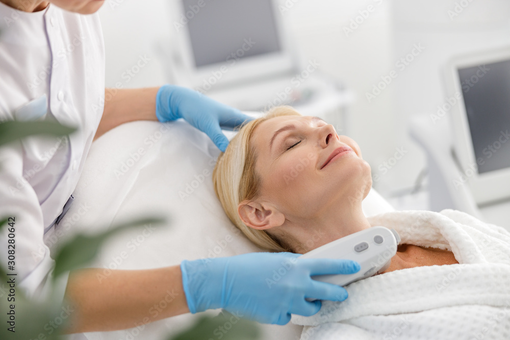 Smiling adult female lying in spa center during procedure Smiling adult female lying in spa center during procedure