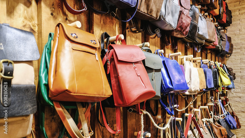 Leather backpacks and briefcases hang on the wall. The concept of stylish leather products. Bags, purses and belts.