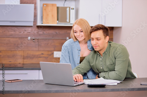 young caucasian man and woman roommates or married couple checking rent or domestic bills to pay online, planning budget or analyzing financial expenses together at home