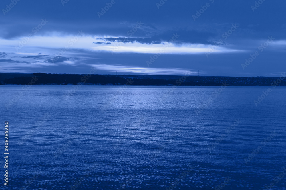 Dark blue night at seaside, dramatic clouds, space for text, selective focus