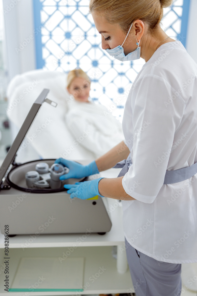 Smiling woman looking on preparation of blood for injections Smiling woman looking on preparation of blood for injections