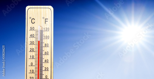 Thermometer in summer day shows or indicate high temperature degree with sun in background.. photo