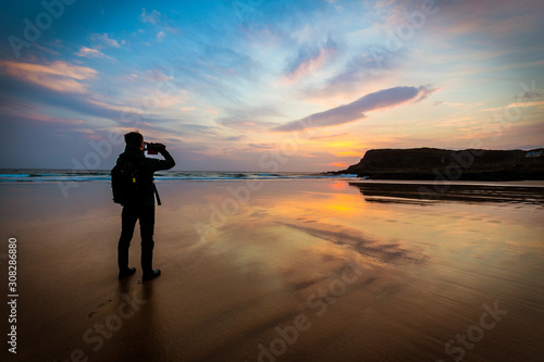 Silhouette of man on a beach taking pictures