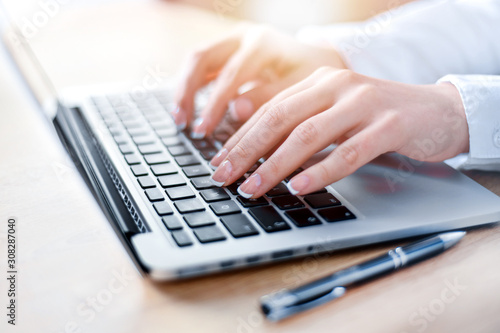 Woman working on modern computer. Laptop keyboard detail with beautiful nails hand.