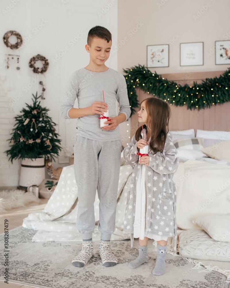 Cheerful brother and sister in their bedroom decorated for Christmas Cheerful brother and sister in their bedroom decorated for Christmas