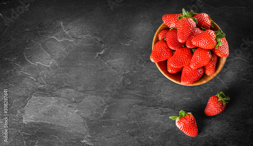 Fresh strawberries in bowl. Strawberry fruits on dark stone table copy space for text top view.