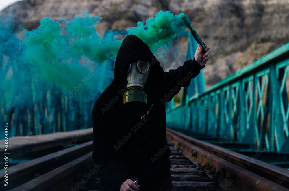 hombre con mascara de gas y bomba de humo azul en un puente azul Stock  Photo
