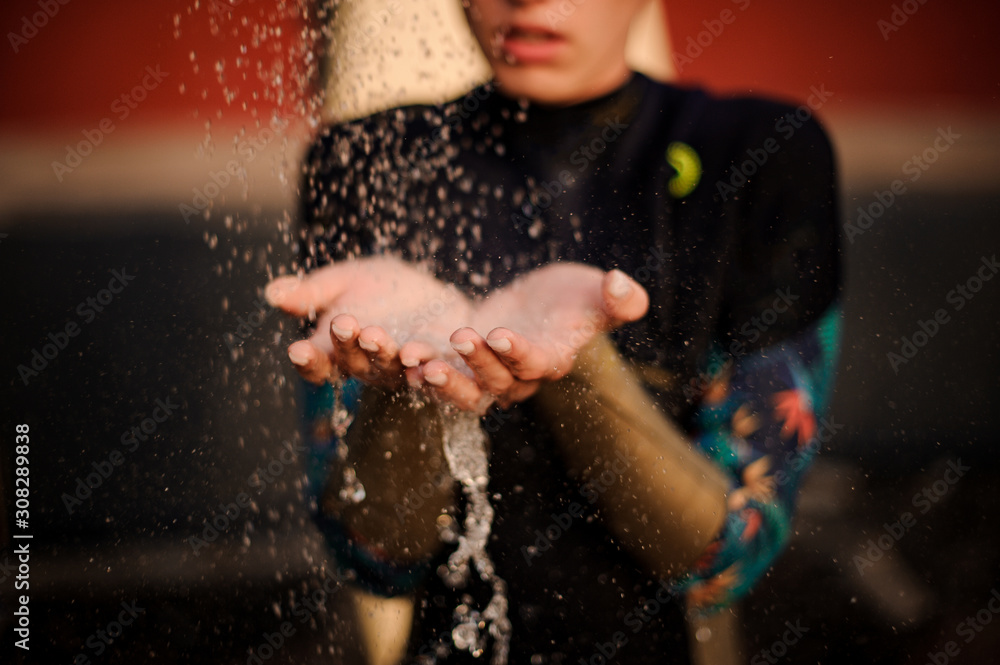 Obraz premium Girl in the black diving suit standing under the shower place hands under water