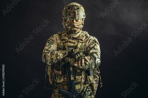 portrait of serious confident brave soldier in army wear, camouflage, isolated over black background. military forces concept