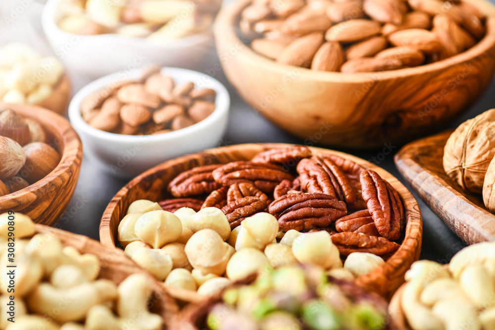 A variety of nuts in wooden bowls from top view. Walnuts, cashew, almond, pistachio, pecan, hazelnut, macadamia nut selection. Healthy super food. A variety of nuts in wooden bowls from top view. Walnuts, cashew, almond, pistachio, pecan, hazelnut, macadamia nut selection. Healthy super food.