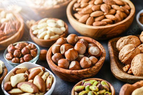 A variety of nuts in wooden bowls from top view. Walnuts, cashew, almond, pistachio, pecan, hazelnut, macadamia and peanut mix selection. Healthy fitness super food.