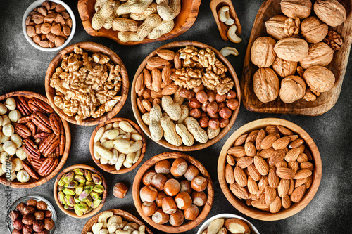 A variety of nuts in wooden bowls from top view. Walnuts, cashew, almond, pistachio, pecan, hazelnut, macadamia and peanut mix selection. Healthy fitness super food.