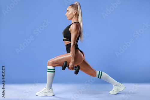 Fitness woman doing lunges exercises for leg muscle workout training. Active girl doing front forward one leg step lunge exercise, on the blue background