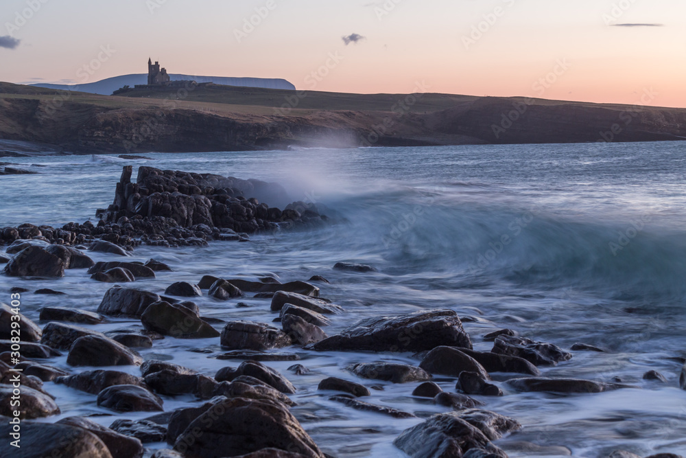 Sunset over Classiebawn castle in the and breaking wave