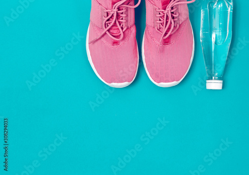 Pink sneakers and bottle of water on an azure background. Concept healthy lifestyle, sport and diet. 