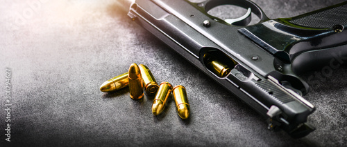 Fotografie Hand gun with ammunition on dark stone background