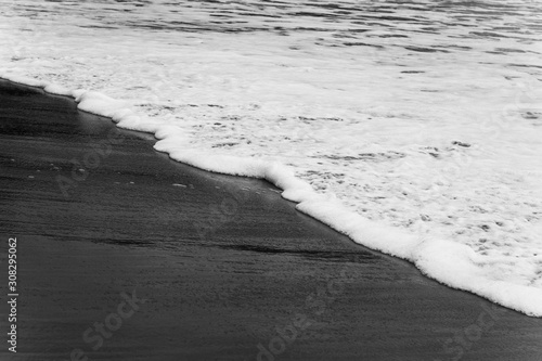 black and white photo of white sea foam in the sand  sea background  sandy beach