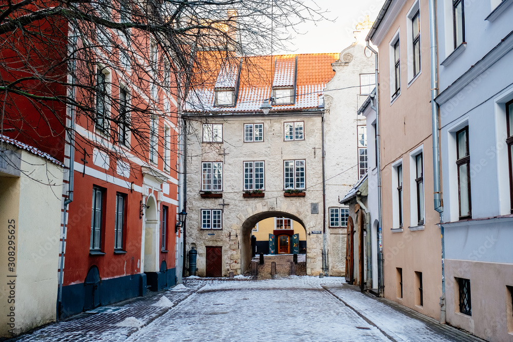 Swedish gate is a famous medieval architectural ensemble in old Riga city, Latvia. Front view on medieval cobblestone narrow street in cold winter day.