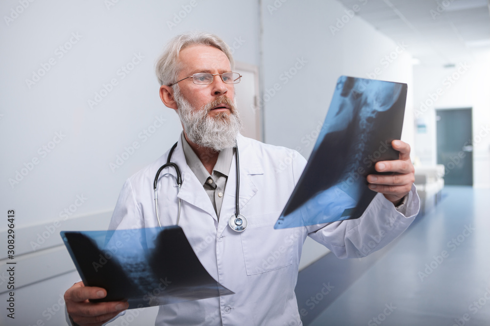 Senior male doctor examining x-ray scans in the hospital Senior male doctor examining x-ray scans in the hospital