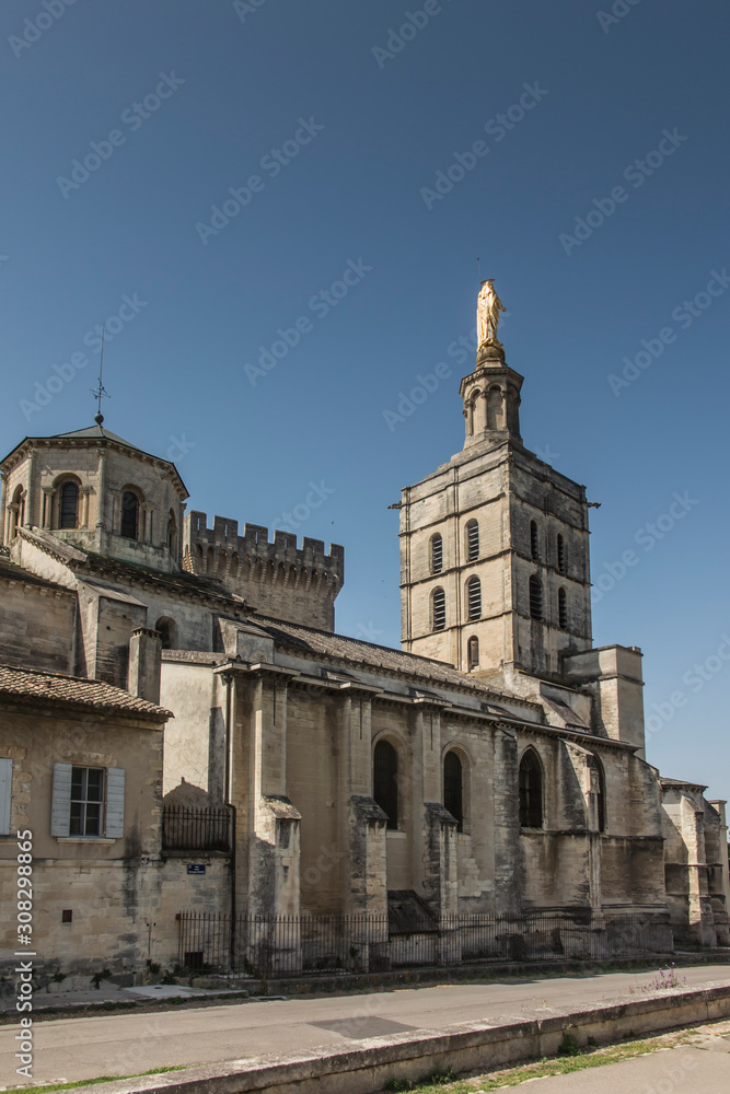 Avignon cathedral (Cathedral of Our Lady of Doms) next to Papal palace (Palais des Papes) under blue sky in Avignon