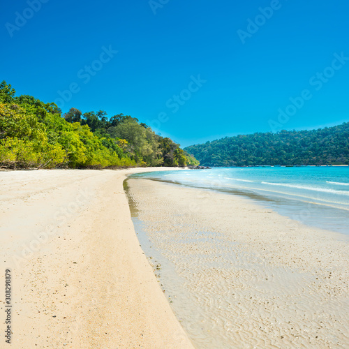 Panorama of beautiful beach at tropical island with white sand and green trees