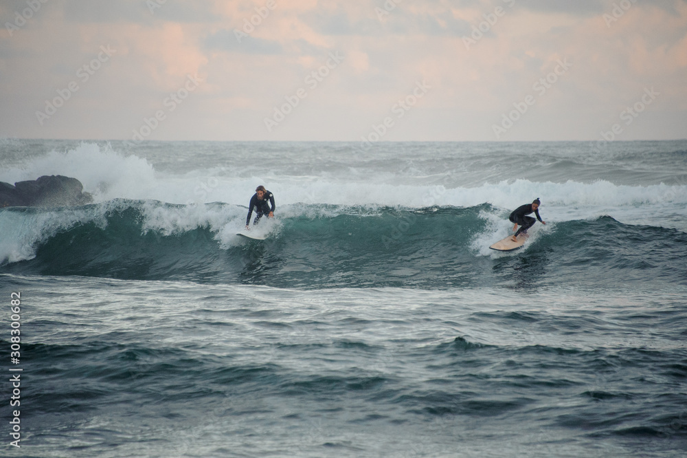 Man and woman surfers caught a small wave on surf boards Man and woman surfers caught a small wave on surf boards