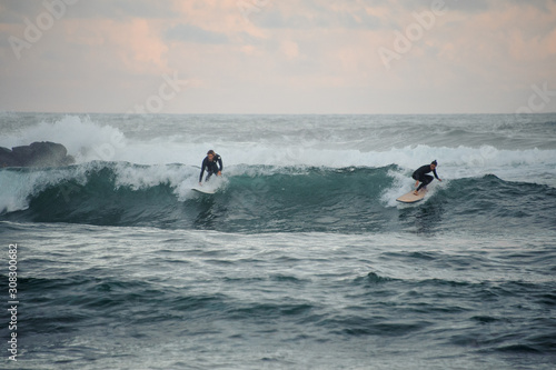 Canvas Print Man and woman surfers caught a small wave on surf boards