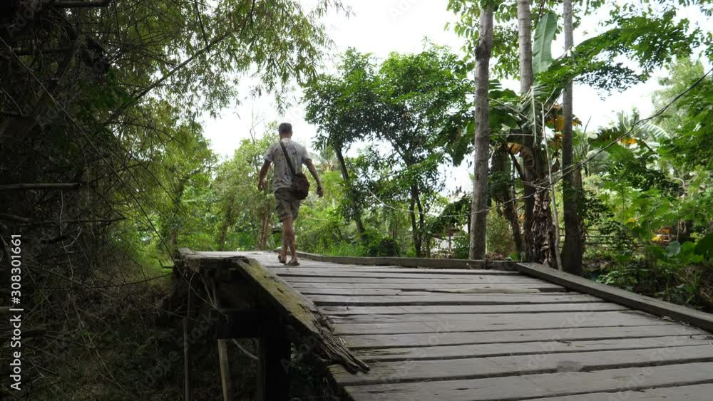 European tourist walks over wooden bridge in country side of Philipinnes European tourist walks over wooden bridge in country side of Philipinnes