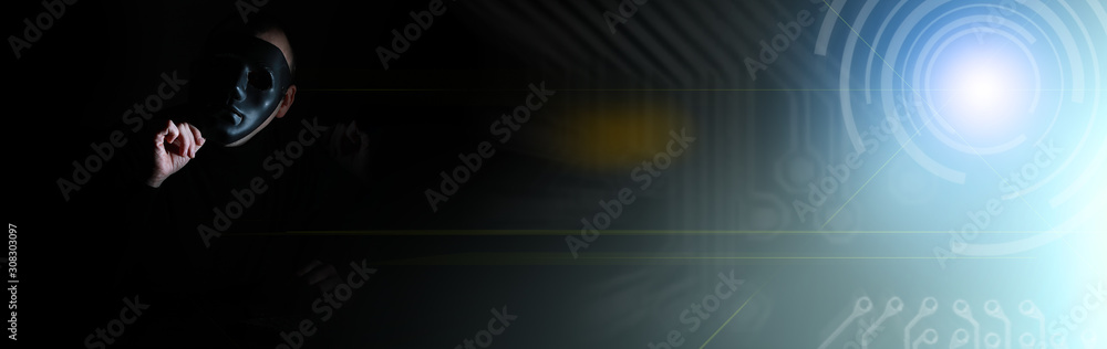 A man in a mask prints on the keyboard in the dark A man in a mask prints on the keyboard in the dark