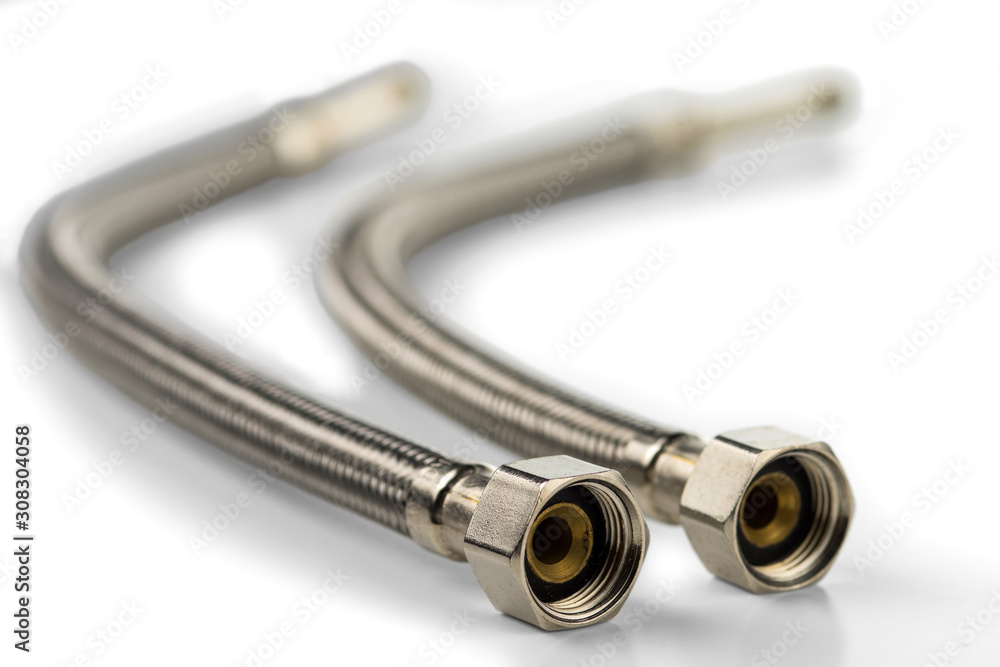 Water flexible hoses in metallic braiding for connection to water sources. On white background. Selective focus. Water flexible hoses in metallic braiding for connection to water sources. On white background. Selective focus.
