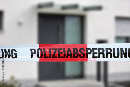 Absperrband mit der Aufschrift Polizeiabsperrung, im Hintergrund ein Wohnhaus